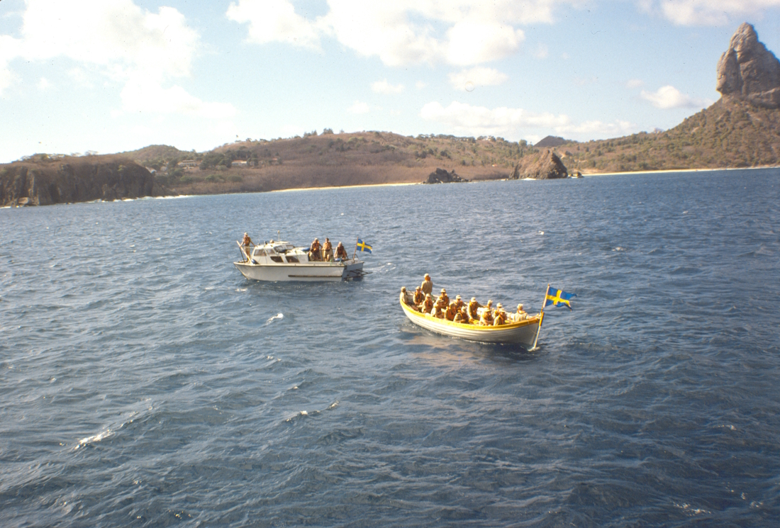 Besättningen tar sig in till stranden i småbåtar och simmar sista biten.