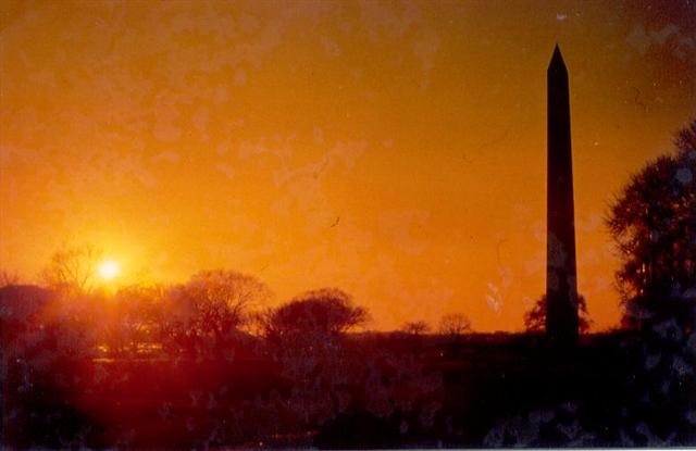 Washington Memorial i solnedgången. Runt basen finns en ring med 50 stjärnbanér var och ett symboliserande en delstat.